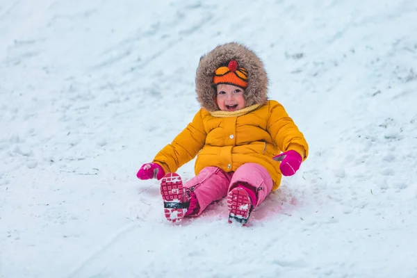 Μικρό παιδί στο έλκηθρο γλιστράει κάτω από το λόφο το χειμώνα — Φωτογραφία Αρχείου
