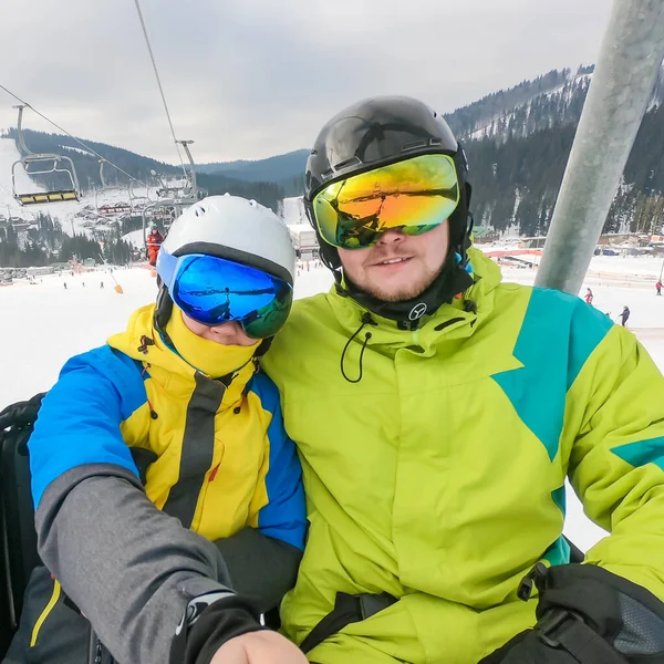 Pareja tomando selfie en equipo de esquí mientras levantan hasta la colina —  Fotos de Stock