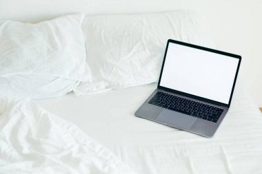 beyaz sayfalı yatakta boş ekranı kopyalayan dizüstü bilgisayar