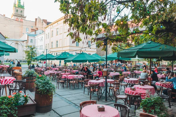 Lviv, Ucrania - 5 de septiembre de 2019: las personas que comen hablando beben en el restaurante cafetería al aire libre — Foto de Stock