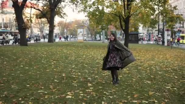 Молодая красивая женщина прогуливается по парку в осеннем наряде — стоковое видео