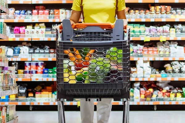 Mujer con compras entre estante de la tienda — Foto de Stock