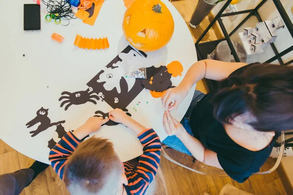 Young mother with toddler son making craft spiders for halloween holiday — Stock Photo, Image