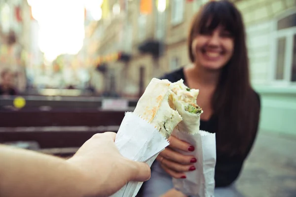 Młoda uśmiechnięta kobieta jedząca fast food na zewnątrz — Zdjęcie stockowe