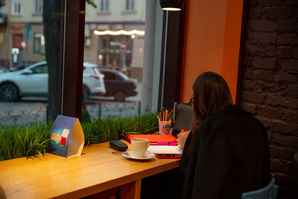 Woman sitting in cafe drinking warm up tea working drawing at same time — Stock Photo, Image