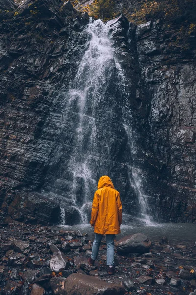 Femme en imperméable jaune à la cascade d'automne — Photo