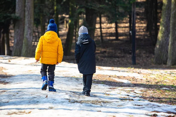 Two boys in winter clothes walking by snowed park — Stock Photo, Image