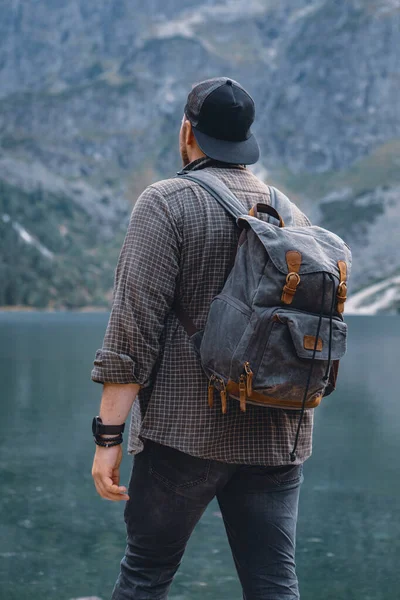 Человек с рюкзаком на озере в горах туристическая концепция — стоковое фото