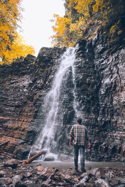 Wanderer blickt auf herbstlichen Wasserfall — Stockfoto