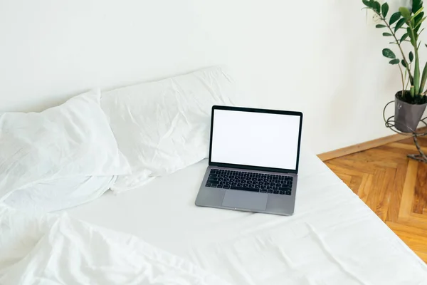 Laptop com espaço de cópia tela vazia na cama com folhas brancas — Fotografia de Stock