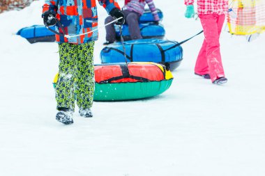 children sliding snow tube down by snowed hill