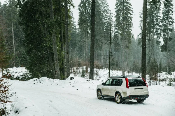 SUV αυτοκίνητο με αλυσίδα σε τροχούς στο χιονισμένο δάσος — Φωτογραφία Αρχείου