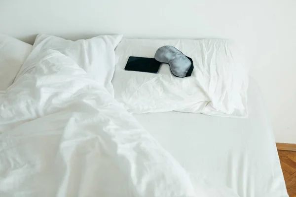 Maska sypialna z telefonem w łóżku z białymi prześcieradłami słoneczny poranek — Zdjęcie stockowe