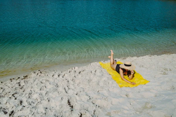 Mulher que coloca em cobertor amarelo banhos de sol na praia de areia — Fotografia de Stock