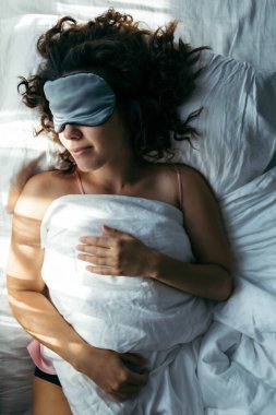 Maskeyle uyuyan bir kadın. Yüzünde parlak bir ışık.