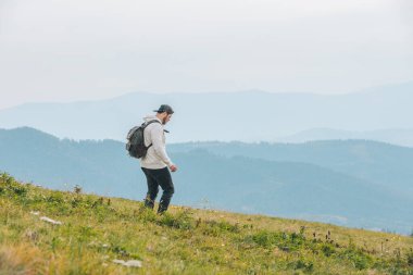 Sırt çantalı bir adam dağda yürüyüş yapıyor.
