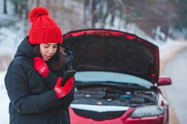 woman calling for help with broken down car at winter highway