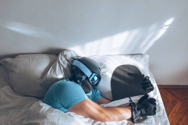 Snowboard kayak yapan bir adam Google ve miğferiyle yatakta.
