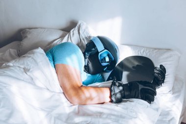 Snowboard kayak yapan bir adam Google ve miğferiyle yatakta.