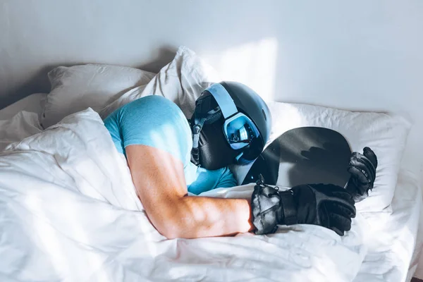 Man in bed with snowboard ski googles and helmet — Stock Photo, Image
