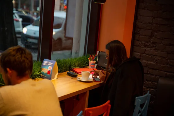 Lviv, Ukraine - September 30, 2018: woman sitting in cafe drinking warm up tea working drawing at same time — Stock Photo, Image