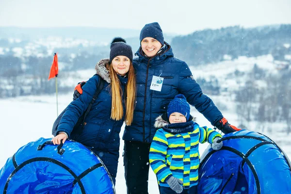 Jonge familie poseren met sneeuw buizen. wintertijd — Stockfoto