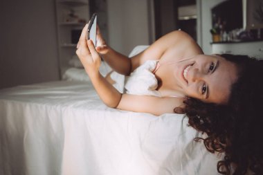 Yatakta genç bir kadın. Pencereden sabah ışığı.