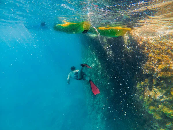 Hombre bajo el agua en aletas mirando el fondo del mar —  Fotos de Stock