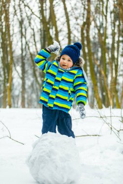 Küçük çocuk karla oynuyor. kartopu yapmak.