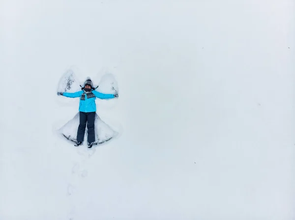 Oversiktskvinne som lager snøengel – stockfoto