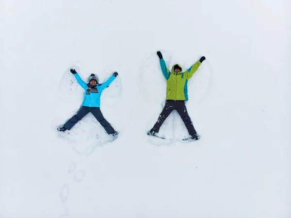 Casal se divertindo fazendo anjo da neve — Fotografia de Stock