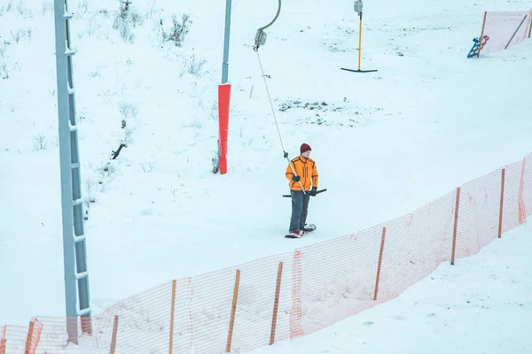 Homem em snowboard usando elevador jugo para obter o pico da colina . — Fotografia de Stock