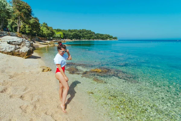 Sexy donna in costume da bagno rosso e t-shirt bianca in spiaggia mare — Foto Stock