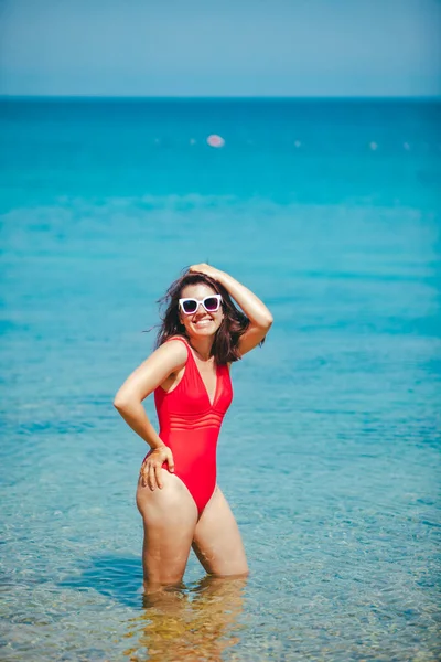 Leende sexig kvinna i röd baddräkt i havsvatten — Stockfoto