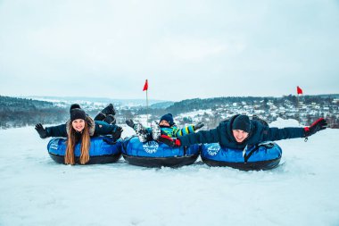 Kar tüpleriyle poz veren genç bir aile. Kış zamanı