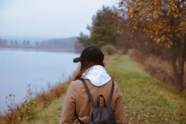 Donna che cammina in riva al lago in abito autunnale — Foto Stock