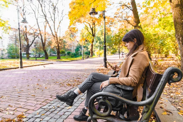 Sonbahar sonbahar sezonunda şehir parkı bankında oturan genç yetişkin moda kadın — Stok fotoğraf