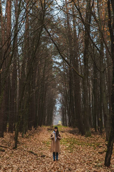 Жінка в осінньому вбранні, що йде лісом — стокове фото
