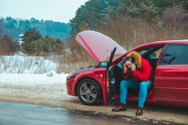 Egy férfi ül az autóban és segítséget kér. meghibásodás a téli gyorsforgalmi úton — Stock Fotó