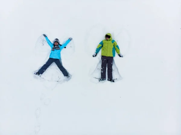 Par har kul att göra snö ängel — Stockfoto