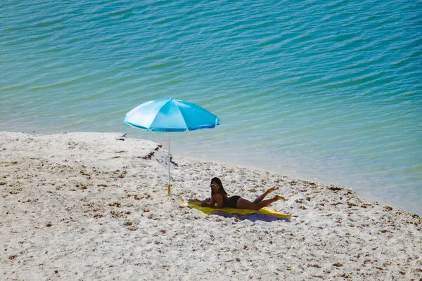 Frau im Badeanzug spazieren am Sandstrand Blauer Sonnenschirm und gelbe Decke — Stockfoto