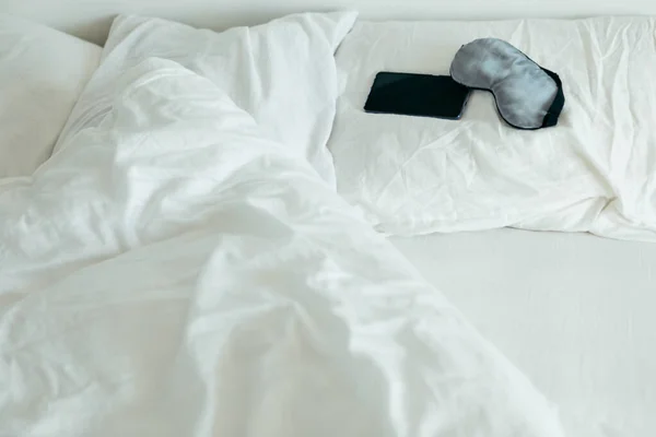 Masca de dormit cu telefon la pat cu foi albe dimineață însorită — Fotografie, imagine de stoc