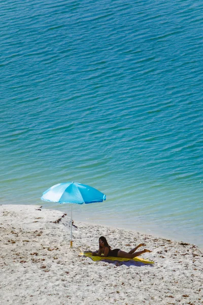 Frau im Badeanzug spazieren am Sandstrand Blauer Sonnenschirm und gelbe Decke — Stockfoto