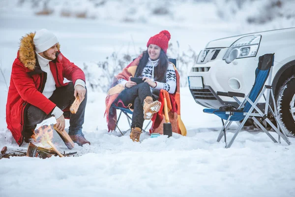 겨울에 남자와 여자 가 캠프 불근처 의자에 앉아 있다. 자동차 여행. — 스톡 사진