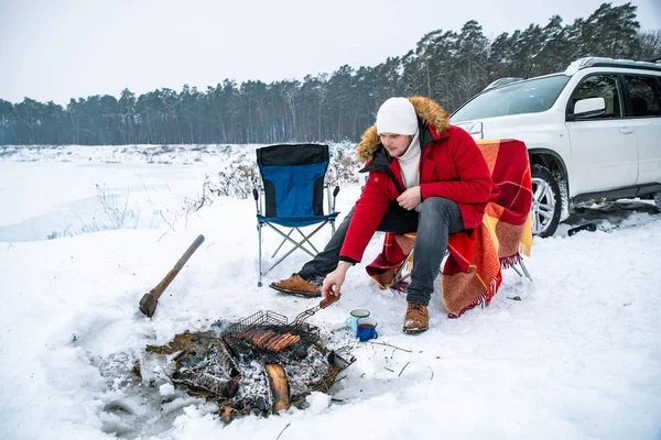 냉동 호수 근처에서 불에 구운 고기를 구워 먹고 있어요. 배경 의 SUV 차량 — 스톡 사진