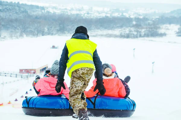 Vinterroliga aktiviteter. Cykla ner för backen på snöslangar — Stockfoto