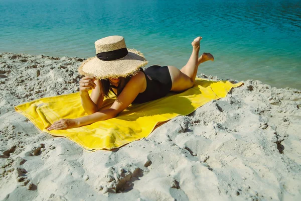 Frau liegt auf gelber Decke und sonnt sich am Sandstrand — Stockfoto