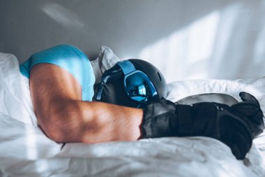 Snowboard kayak yapan bir adam Google ve miğferiyle yatakta.