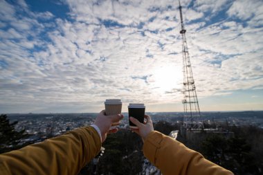 Kadın ve erkek el ele kahve fincanları tutuyor.
