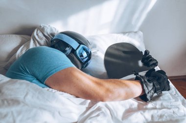 Snowboard kayak yapan bir adam Google ve miğferiyle yatakta.